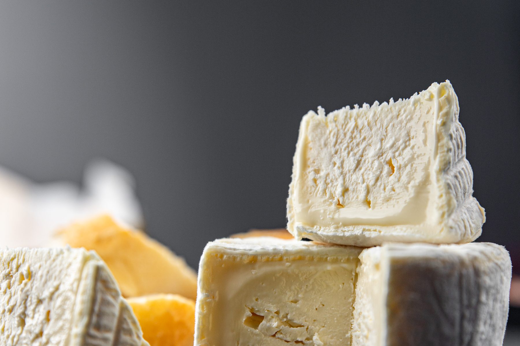 A still life of farmhouse cheeses, cut to show their rind and paste