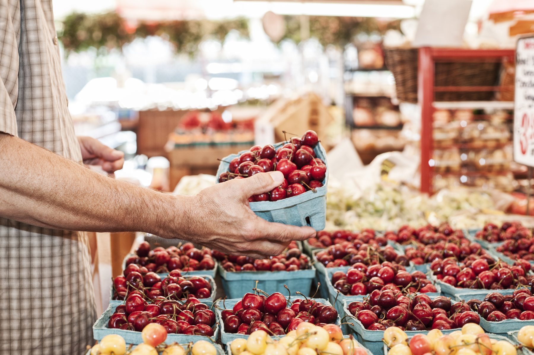 Hands choosing a punnet of cherries at a farmers market